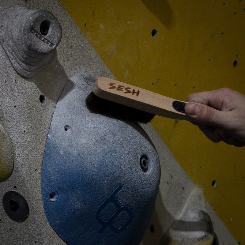 Brushing chalk off a climbing hold with a Sesh boar-bristle brush